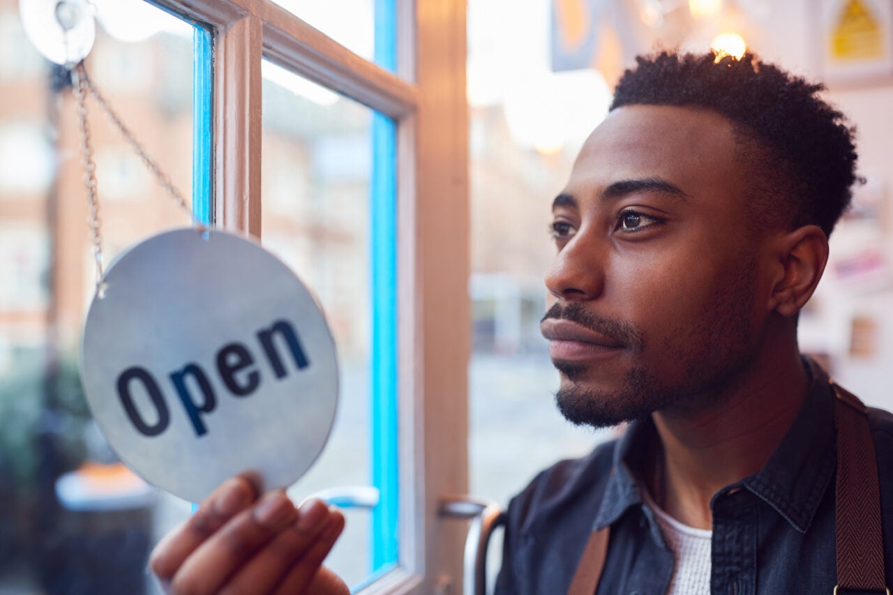 Small Business Owner Turning Around Open Sign On Shop