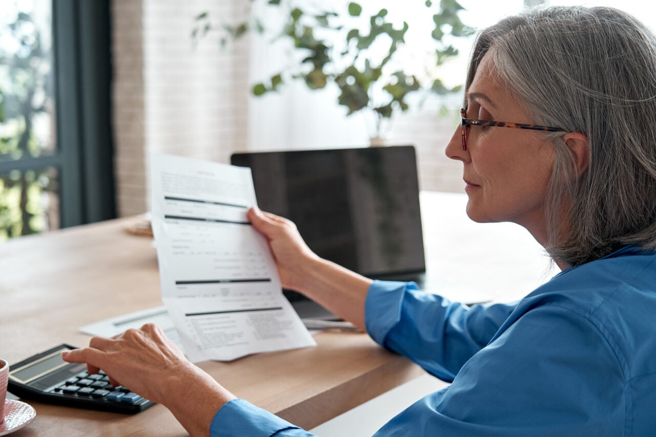 Senior Mature Business Woman Holding Paper Bill Using Calculator